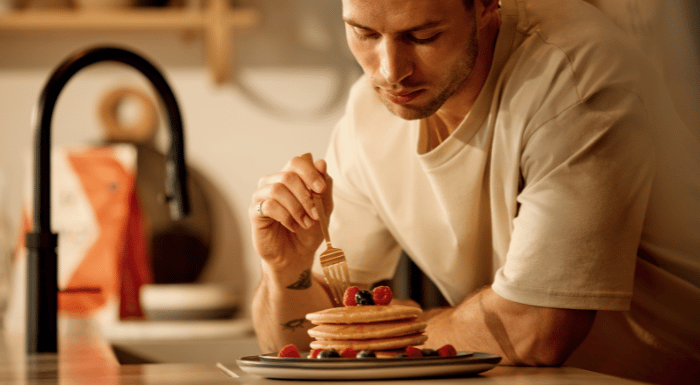 A man eating a stack of protein pancakes.
